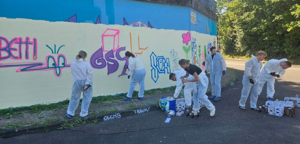 schüler beim gemeinsamen graffitisprühen